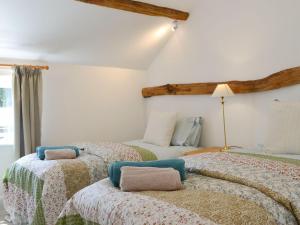two beds in a room with white walls at The Hop Cottage in Ashperton