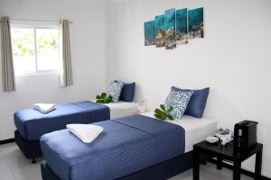 Habitación con 3 camas en azul y blanco en Surf Yoga Camp, en Thulusdhoo