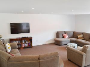 a living room with two couches and a flat screen tv at Reeds Farmhouse in Bentley