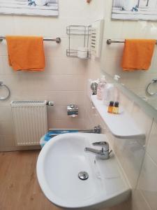 y baño con lavabo blanco y toallas de naranja. en Ferienwohnung - Landhotel Waldschlößchen en Sohland