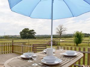 a wooden table with a blue umbrella on a patio at The Little Barn in High Halden