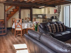 a living room with a leather couch and a table at Uk40277 - Llys Elen Two in Brynsiencyn