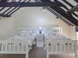 two white beds in a room with white walls at Uk40277 - Llys Elen Two in Brynsiencyn