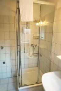 a shower with a glass door in a bathroom at Ellada Restaurant & Hotel in Tarp