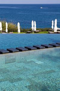 a swimming pool with chairs and the ocean in the background at Anassa in Polis Chrysochous