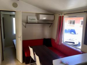 a small room with a red couch and a window at De Pujol Greenchalets Argeles sur Mer in Argelès-sur-Mer