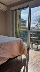 a bedroom with a bed and a balcony with a view at Departamento Caseros in Salta
