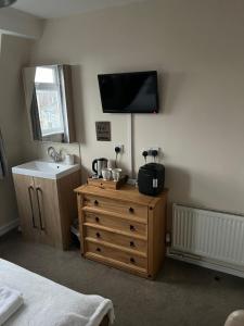 a bedroom with a dresser with a television on the wall at Willows Guest House in Great Yarmouth