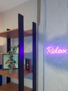 a neon sign that says relax on a wall at Relax Sampa in Sao Paulo