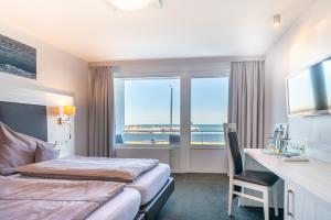 a hotel room with two beds and a desk and window at Hotel Hochseeinsel in Helgoland