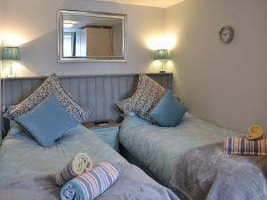 マラザイオンにあるBeach Comber Cottageのベッドルーム1室(青い枕と鏡付きのベッド2台付)