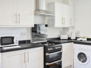 a white kitchen with a stove and a microwave at The Coach House At Mount Pleasant in New Shildon