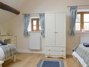 a bedroom with two beds and a white cabinet at No, 2 Ash Cottage in Quatt