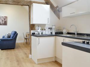 a kitchen with white cabinets and a blue chair at No, 2 Ash Cottage in Quatt