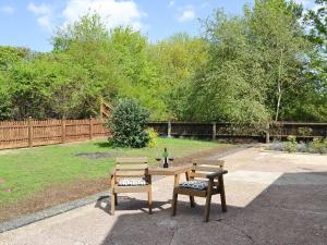 a wooden table with two chairs and a bottle of wine at The Waiting Rooms in Cawston