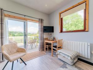 a living room with a chair and a table and a window at Cwtch Enrico - Uk39064 in Scyborycoed