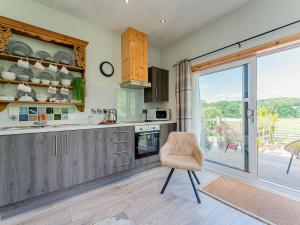 a kitchen with a chair in front of a sliding glass door at Cwtch Enrico - Uk39064 in Scyborycoed