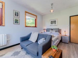 a bedroom with a bed and a blue couch at Cwtch Enrico - Uk39064 in Scyborycoed