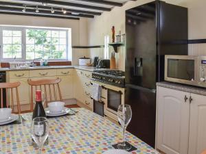 a kitchen with a table with wine glasses and a refrigerator at Uk40278 - Llys Elen One in Brynsiencyn