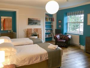 1 dormitorio azul con 2 camas y 1 silla en The Moat House, en Annan