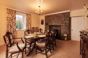 a dining room with a table and a stone fireplace at Castell Y Waun- Beautiful and spacious country farmhouse with luxury Hot Tub & Grounds in Carmarthen