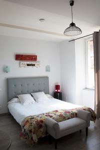 a white bedroom with a large bed and a chair at AYATO l’auberge de l’abbaye in Sorde-lʼAbbaye