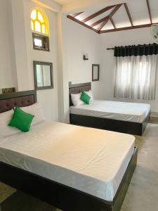 a bedroom with two beds with green pillows at Tropical Vibes - Kathaluwa in Ahangama