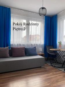 a living room with a couch and blue curtains at Krysia - tuż przy plaży in Mielno