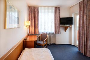 a hotel room with a desk and a bed and a television at Hotel Am Steinberg in Hildesheim