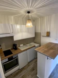 una cucina con armadi bianchi e lampadario pendente di Studio cabine avec jardin a Canet-en-Roussillon