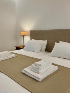 2 camas con sábanas blancas y toallas. en Quinta da Porta - Solar de Vale de Prazeres en Vale de Prazeres