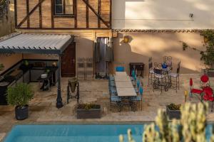 un patio con mesa, sillas y piscina en Maison Toscane in a remarkable village - heated pool, jacuzzi, billiard & ensuite luxury bedrooms en Terraube