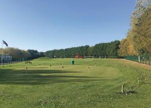 a large grassy field with a playground in the background at Woodthorpe Leisure Park in Strubby