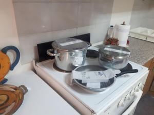 three pots and pans on a stove in a kitchen at Cosy and roomy 78m2(Μονοκατοικία) in Piraeus