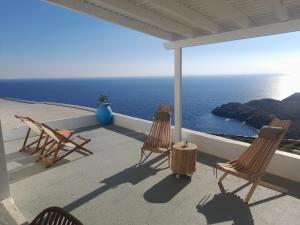 drie stoelen en een tafel op een balkon met uitzicht op de oceaan bij Sofia sea view house in Faros