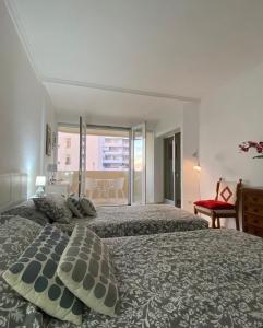 een slaapkamer met 2 bedden en een groot raam bij Estepona Port Apartment in Estepona