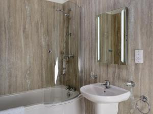 een badkamer met een wastafel, een bad en een spiegel bij The Old Forge in Saxilby