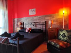 1 dormitorio con 1 cama, 1 silla y paredes rojas en Hotel Transilvania, en Pian del Voglio