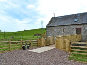 a barn with a wooden fence next to a building at Bridge Cottage in New Channelkirk