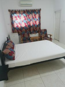 a large white bed in a room with a chair at TRANQUIL RESORT HOTEL in Brusubi