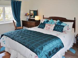 a bedroom with a large bed with a blue comforter at Forge Cottage in Stiffkey