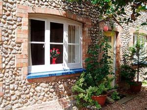 a window of a stone house with flowers in it at Forge Cottage in Stiffkey