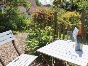 a white picnic table with a bottle of wine on it at Forge Cottage in Stiffkey