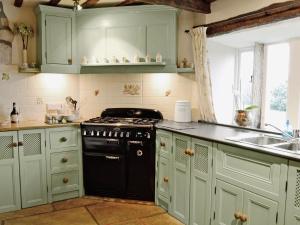 a kitchen with green cabinets and a stove and a sink at Far View Cottage in Haworth