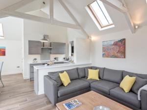 a living room with a gray couch and yellow pillows at The Old Piggery in Sidbury