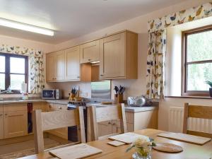 a kitchen with wooden cabinets and a table with chairs at Stildon Manor Cottage in Pensax