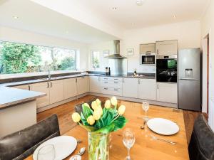 a kitchen with a table with yellow tulips in a vase at Robins Nest in Kirkcudbright