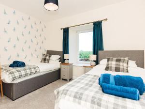 1 dormitorio con 2 camas y ventana en Robins Nest en Kirkcudbright