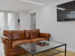 sala de estar con sofá de cuero marrón y mesa de cristal en Hollies Cottage 4 - Ukc4517 en Martock