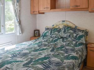 a bedroom with a bed with a green and white comforter at Spinney Retreat in East Wellow